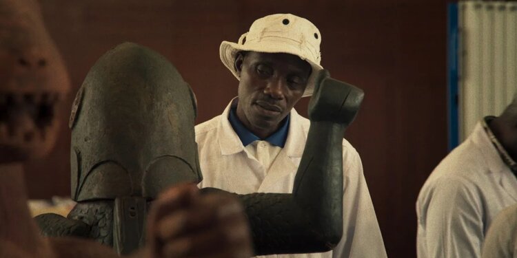 A museum worker examines a returned Beninese artifact in Dahomey by Mati Diop.